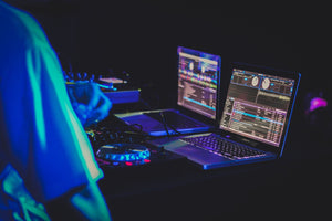 Person facing computers and DJ essentials