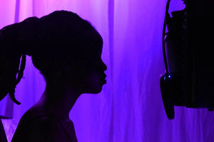 Silhouette of a woman in a studio singing into a microphone